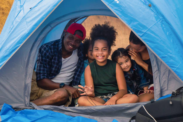 african american family, parent with kids, and asian adoped child having fun together in camping at natural park